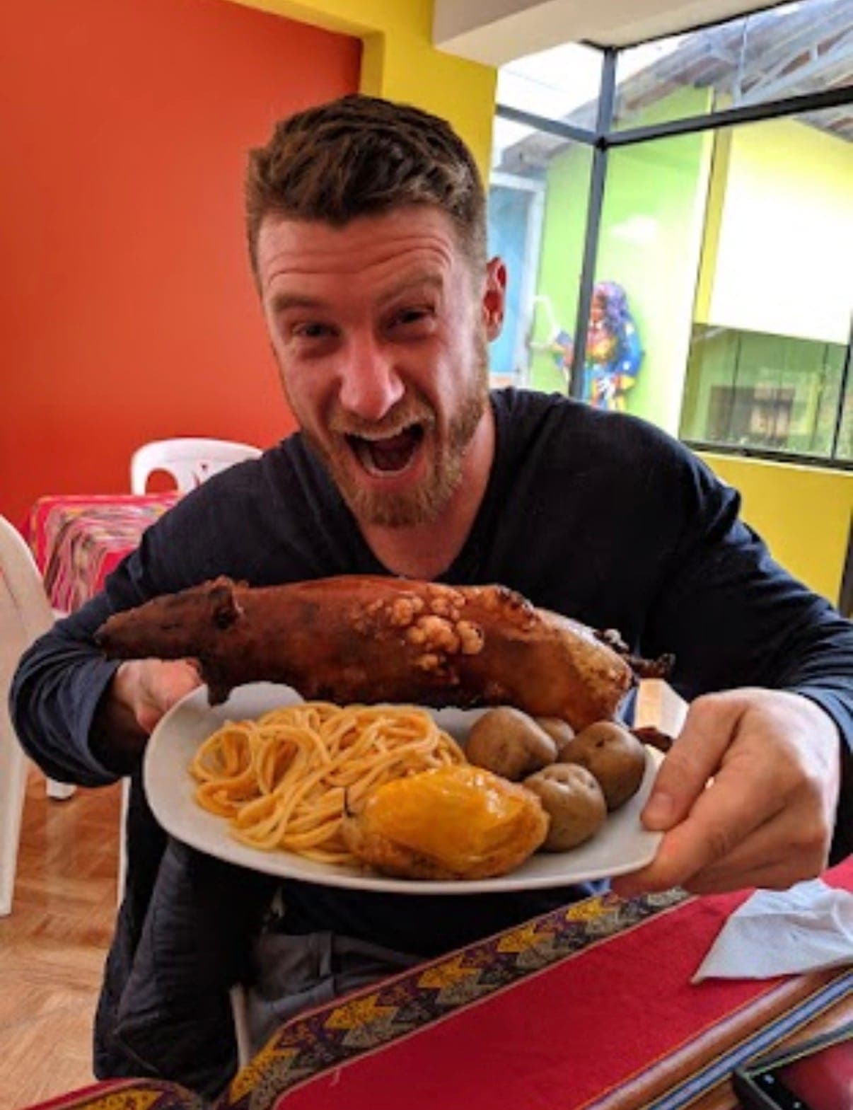 guy holding a plate of cuy